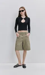 Top de calce al cuerpo color negro, confeccionado en tejido elástico con textura acanalada, con cuello camisero, mangas largas y recorte frontal tipo cut-out.