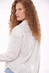 Camisa blanca con estampado dorado, de corte recto, manga larga y cuello clásico.