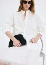 Camisa oversize blanca de mezcla de algodón y lyocell, con cuello camisero, manga larga, puños abotonados y detalle de perlas aplicadas en toda la prenda.