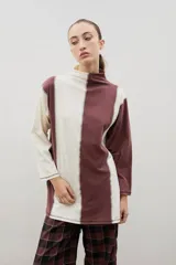 Polera de manga larga con diseño bicolor en bloques verticales, confeccionada en algodón. Presenta cuello alto y tajos laterales en el ruedo.