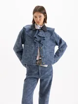Chaqueta de denim Panamá azul de 100% algodón, con volados en el frente y cuello de cuero vacuno negro contrastante. Cuenta con bolsillos frontales con solapa y cierre de botones metálicos.
