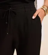 Pantalón de vestir femenino color marrón oscuro, de corte fluido y tiro medio/alto, con cintura elástica ajustable mediante cordón. Presenta bolsillos laterales y cierre frontal.