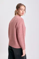 Buzo de punto en color rosa viejo, de cuello redondo, manga larga y diseño holgado con puños y ruedo acanalados.