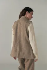 Chaleco color crema con solapas, corte entallado y bolsillos plaqué.