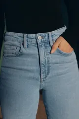 Jeans de tiro alto color marrón oscuro con acabado lavado, corte recto/flare y bajo cropped sin costuras. Presenta cinco bolsillos y cierre frontal con cremallera y botón metálico.