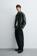 Cazadora de corte relajado confeccionada en tejido efecto piel. Presenta cuello solapa, cierre frontal con cremallera oculta por solapa con botones a presión, bolsillos de plastrón con solapa en la parte frontal y bajo ajustable con elástico en los laterales.