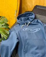 Canguro oversized color azul con capucha, cordones ajustables en color crema, bolsillo canguro frontal y logo bordado en el pecho con diseño de olas.