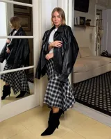 Pollera midi de corte irregular con diseño de cuadros escoceses en tonos grises y negros. Presenta un estilo asimétrico con caída fluida y terminación en punta.