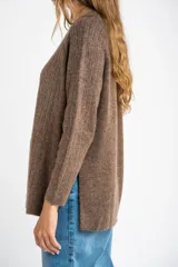 Sweater de punto texturado en color beige, con cuello redondo y mangas largas. Presenta un diseño de tejido acanalado vertical y corte holgado.
