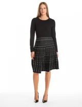 Vestido midi de punto con cuerpo liso negro de manga larga y falda acampanada con patrón geométrico vertical en contraste. Presenta escote redondo a la base y diseño entallado.