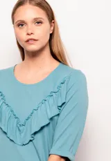 Remera celeste de manga larga con cuello redondo y volados diagonales en el frente.