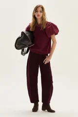 Blusa blanca de calce recto con cuerpo de jersey y mangas cortas tipo globo en popelina. Presenta cuello redondo y detalle de bordado decorativo en la espalda.