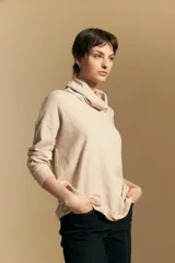 Polera de tejido de punto color naranja con cuello alto de caída relajada y diseño de líneas en relieve. Presenta una silueta holgada con hombros caídos y mangas largas.