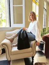 Bolso tipo tote bag negro de cuero, con costuras a la vista y manijas cortas.