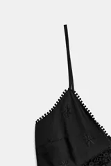 Vestido midi negro con escote en pico, tirantes finos y detalles de bordados y encaje en el escote y el bajo.