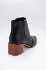 Botas cortas de cuero color beige, con punta fina y cierre lateral. Tienen un taco cuadrado de madera.