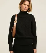 Suéter de manga larga confeccionado en tricot, con cuello alto y diseño de bordado de rombos en relieve. Presenta puños y ruedo acanalados.