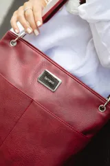 Bandolera negra de cuero sintético con dos bolsillos frontales, cierre metálico y dos correas intercambiables: una de cuero sintético y otra de tela con rayas rosas y negras.