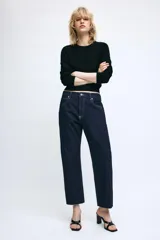 Jeans de tiro medio confeccionados en denim azul oscuro, con diseño de cinco bolsillos, trabillas para cinturón y bajo deshilachado. Cierre frontal con cremallera y botón metálico.