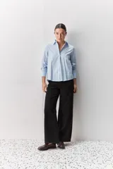Camisa de algodón blanca, de calce relajado, con cuello clásico, mangas largas y cierre frontal con botones.