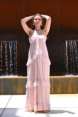 Vestido largo color rosa, con escote halter, corte imperio, falda con volados y espalda descubierta.