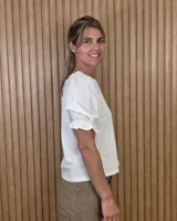 Blusa blanca de corte recto con escote a la base y mangas cortas abullonadas con terminación fruncida.