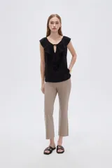 Blusa negra de viscosa sin mangas, con cuello redondo, volados frontales y detalle de lazo en el escote.