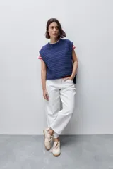 Pantalón jean de tiro alto con calce straight y pierna recta, confeccionado en denim de aspecto limpio. Cuenta con cinco bolsillos, cierre frontal con botón y presillas para cinturón.