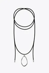 Collar largo de cordón negro con un dije colgante irregular de acero plateado y terminaciones metálicas en los extremos.