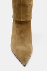 Bota de tacón alto de serraje color camel, con caña alta y diseño de calce fácil. Presenta tacón fino y punta.