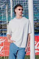 Remera de algodón de corte holgado, color blanco con cuello redondo en tono celeste claro. Presenta un pequeño bordado de la bandera de Uruguay en el pecho.