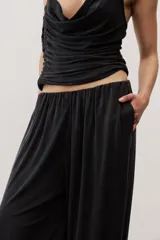 Pantalón holgado negro tipo bombacho, con cintura elástica y puños fruncidos en los tobillos.