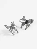 Prendedor doble con forma de moña metálica plateada, con un detalle rectangular negro en el centro de cada moña.