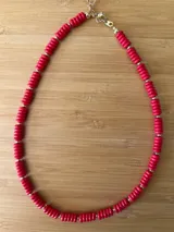Collar corto de cuentas rojas con forma de espiral separadas por pequeñas cuentas doradas. Cierre de mosquetón dorado con cadena de alargue.