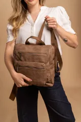 Mochila mediana de cuero sintético con textura rugosa, cuenta con un compartimento principal con cierre, un bolsillo frontal con cierre y correas ajustables de tela.