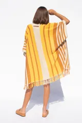 Ruana tejida a rayas horizontales en tonos amarillo, naranja y blanco, con flecos en el borde inferior.