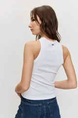 Musculosa blanca de ajuste ceñido con cuello redondo y detalle de apliques metálicos a lo largo de la parte frontal.