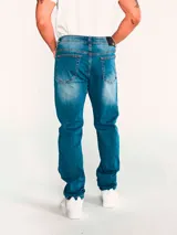 Jeans de mezclilla azul con calce slim, diseño clásico de cinco bolsillos, cierre de cremallera y botón metálico. Presenta efecto desgastado en los muslos y costuras en tono contrastante.