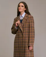 Tapado largo marrón con diseño a cuadros azules, solapas de pico, mangas largas con abertura y botones, bolsillos frontales con tapa y forro interior.