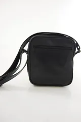 Morral bandolera de cuero genuino color marrón, con diseño compacto, cierre superior y correa ajustable para el hombro.