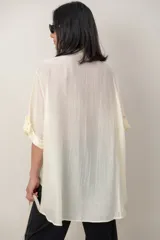 Camisa oversize de seda negra, con cuello camisero, cierre frontal con botones y mangas cortas con vuelta.