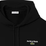 Canguro Lacoste de color negro con capucha y cordones ajustables. Presenta un bolsillo frontal tipo canguro y un pequeño bordado en el pecho con el logo de la marca y la frase 'Jeu Set et Match'.