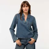 Blusa de jean de corte recto, con cuello polo, escote en V y bolsillo frontal en el pecho. Presenta mangas largas y un diseño de calce holgado.