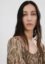 Vestido corto de viscosa con estampado de serpiente, cuello cuadrado y manga larga con puños elásticos. Presenta cintura con goma elástica y forro interior de poliéster.