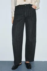 Pantalón de tiro medio con diseño balloon, confeccionado en tejido con patrón de rayas verticales. Presenta cintura con trabillas, cierre frontal con cremallera y botón, y cinco bolsillos.