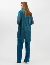 Conjunto de tres piezas compuesto por musculosa, cardigan y pantalón. La musculosa y el cardigan presentan un diseño plisado con hilos metalizados en tonos verdes y azules, creando un efecto tornasolado. El cardigan es de frente abierto con mangas 3/4 y corte fluido. El pantalón es de seda fría en color azul petróleo, con cintura elastizada. Incluye un collar removible.