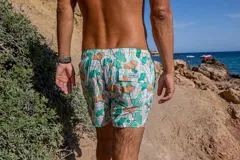 Short de baño Von Braun con estampado botánico de hojas en tonos verdes y naranjas sobre fondo blanco. Cuenta con cintura elástica, dos bolsillos laterales y un bolsillo trasero con solapa y etiqueta de la marca. Incluye interior con mesh hipoalergénico y tela de secado rápido.