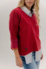 Buzo de punto con escote en V y mangas 3/4, confeccionado en lana suave. Presenta un diseño holgado con tajos laterales y un detalle de parche circular en el frente. El puño de las mangas destaca por un tono contrastante.