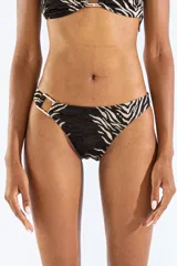 Bombacha de bikini con estampado animal print tipo cebra en tonos negro y beige, confeccionada en jacquard. Cuenta con un aro metálico decorativo en el lateral de la cadera.