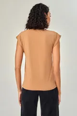 Blusa de poliéster sin mangas, con cuello en V y estampado abstracto multicolor en tonos beige, marrón, negro y naranja.